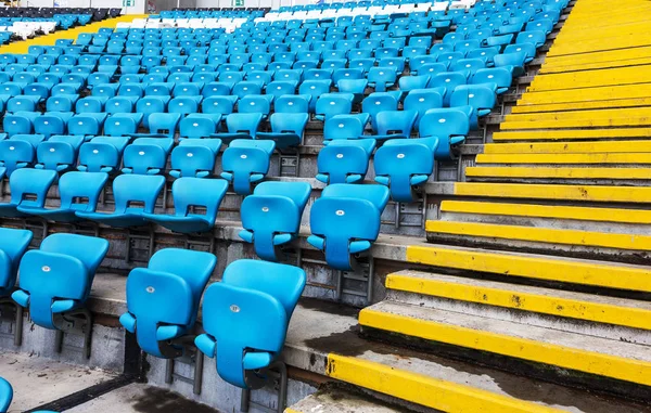 Empty old plastic chairs in the stands of the stadium. Many empty seats for spectators in the stands. Empty plastic chairs, seats for football fans. Tribune, game without spectators