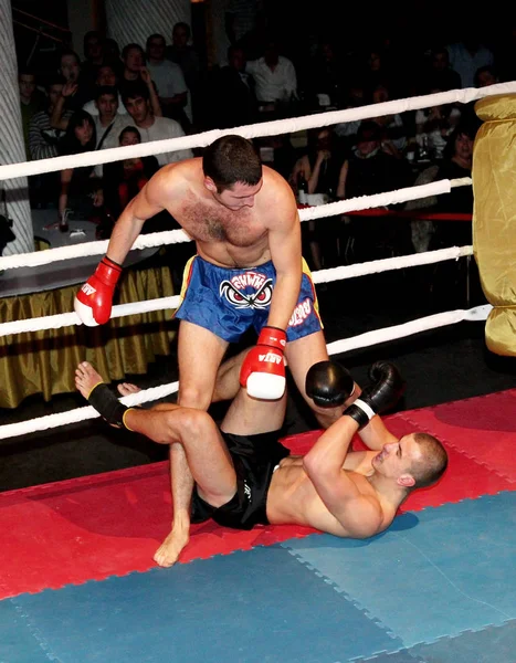 Odessa, Ukraine - October 14, 2010: Fight Club. Fighting without rules. Mixed martial arts fighters compete in the cell, resulting in punches and kicks. The dramatic moment of the battle.