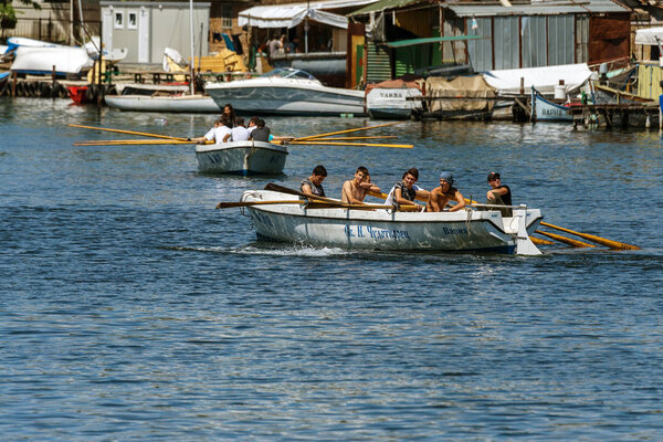 VARNA, BULGARIA - CIRCA 2017: Young athletes train in a rowing team on marine lifeboats in the water area of the port of Varna