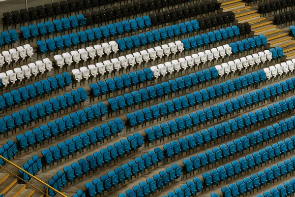 Blank old plastic chairs at the stadium. Number of empty seats in a small old stadium. Scratched worn plastic seats for fans