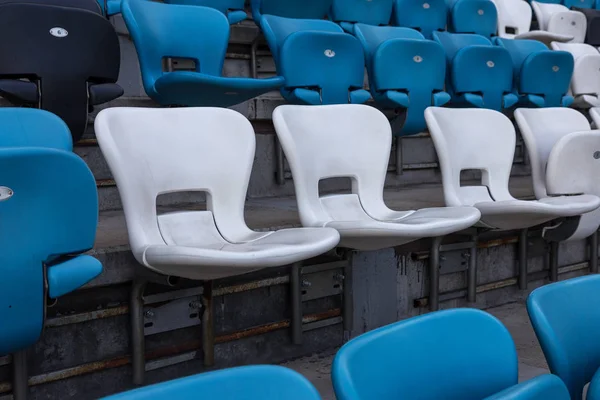 Empty old plastic chairs in the stands of the stadium. Many empty seats for spectators in the stands. Empty plastic chairs, seats for football fans. Tribune, game without spectators