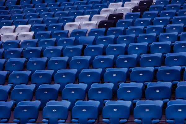 Blank old plastic chairs at the stadium. Number of empty seats in a small old stadium. Scratched worn plastic seats for fans