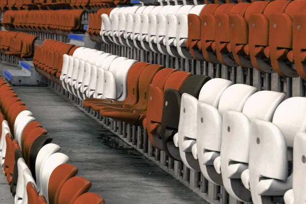 Empty old plastic chairs in the stands of the stadium. Many empty seats for spectators in the stands. Empty plastic chairs, seats for football fans. Tribune, game without spectators