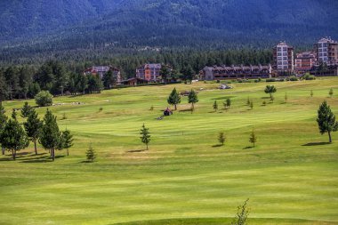 Razlık, Bulgaristan - 29 Temmuz 2016: Pirin Dağı sayısı Todorka ve Vihren en üstündeki. Güzel görünüm yeşil yaz golf sahası. Resort Razlık, Bulgaristan