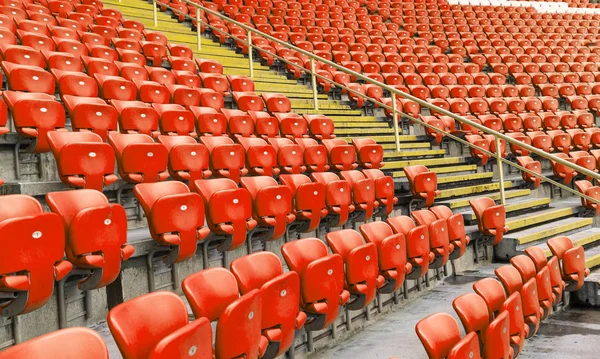 Empty old plastic chairs in the stands of the stadium. Many empty seats for spectators in the stands. Empty plastic chairs, seats for football fans. Tribune, game without spectators