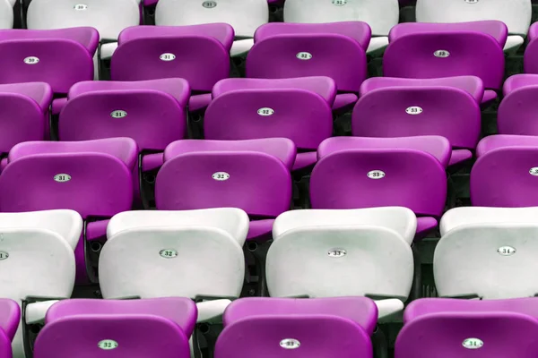 Plastic multi-colored seats for spectators in the amphitheater of the football stadium. Conceptual background of empty seats in the stadium