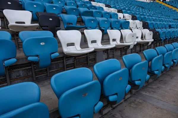 Empty old plastic chairs in the stands of the stadium. Many empty seats for spectators in the stands. Empty plastic chairs, seats for football fans. Tribune, game without spectators