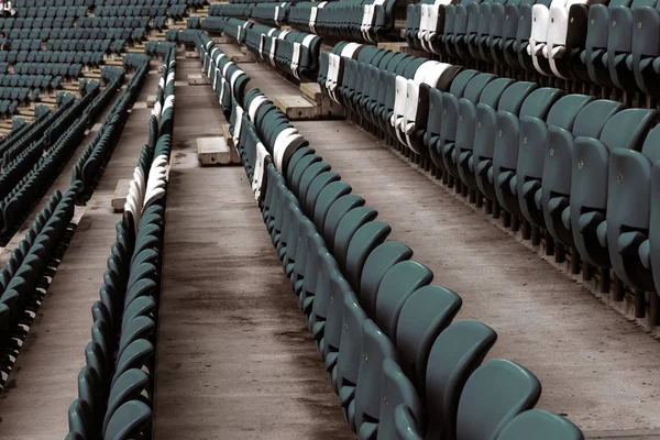 Blank old plastic chairs at the stadium. Number of empty seats in a small old stadium. Scratched worn plastic seats for fans