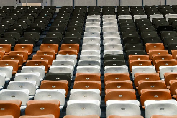 Plastic multi-colored seats for spectators in the amphitheater of the football stadium. Conceptual background of empty seats in the stadium