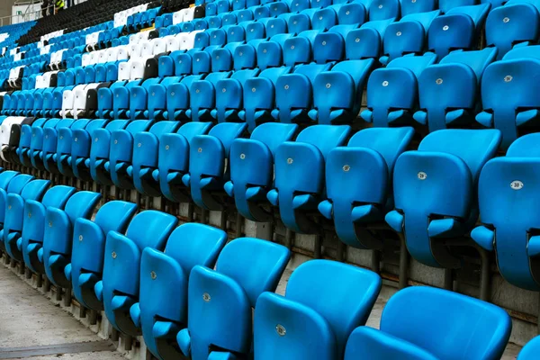 Blank old plastic chairs at the stadium. Number of empty seats in a small old stadium. Scratched worn plastic seats for fans