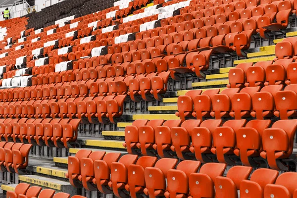 Empty old plastic chairs in the stands of the stadium. Many empty seats for spectators in the stands. Empty plastic chairs, seats for football fans. Tribune, game without spectators