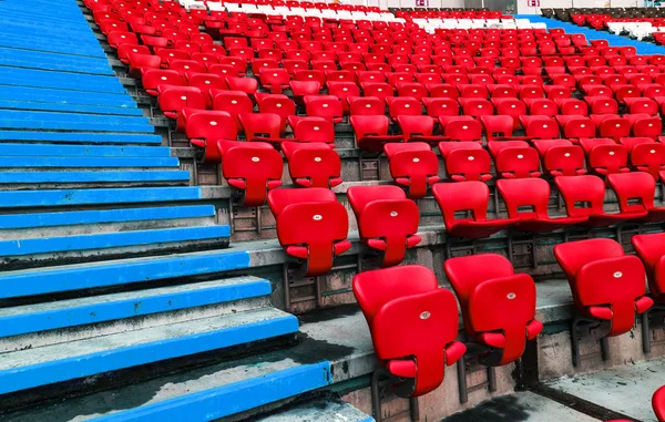 Empty old plastic chairs in the stands of the stadium. Many empty seats for spectators in the stands. Empty plastic chairs, seats for football fans. Tribune, game without spectators