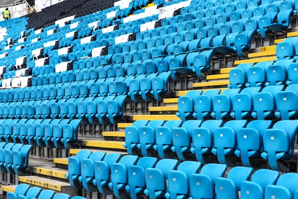 Empty old plastic chairs in the stands of the stadium. Many empty seats for spectators in the stands. Empty plastic chairs, seats for football fans. Tribune, game without spectators