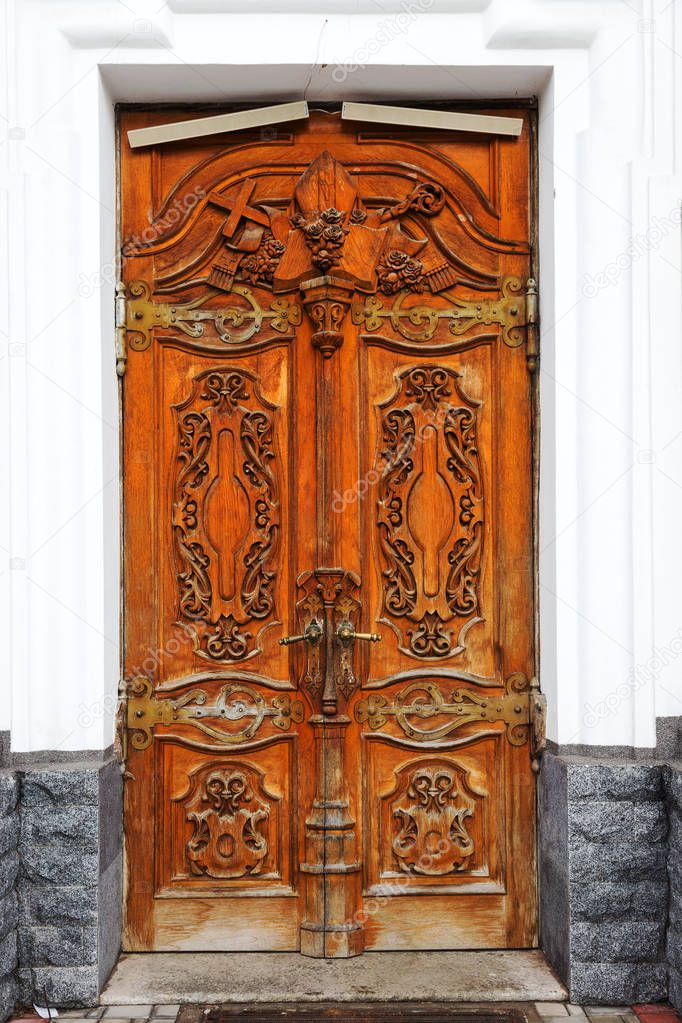 The old wooden door. Ancient antique wooden in an old wall. Ancient decorative wooden door. Historical art style facade of an elite expensive antique door. Wooden background, old front door, vintage element