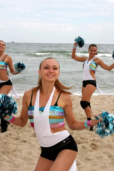 Odessa, Ukraine - September 4, 2010: Bright dynamic performance of the women's support group sports team on the sandy shores of the Black Sea. Cheerleaders in Aktion. Bright beautiful young girl in sportswear