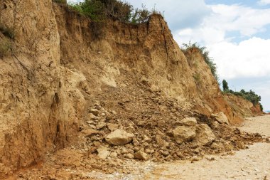 Çevreye zararlı bir bölgede dağ heyelan. Yeryüzündeki büyük çatlaklar, toprak yolu kapatan büyük katmanların inişi. Dağ yamacının yamacında baraj tehlikesi