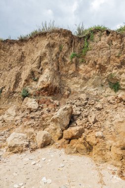 Çevreye zararlı bir bölgede dağ heyelan. Yeryüzündeki büyük çatlaklar, toprak yolu kapatan büyük katmanların inişi. Dağ yamacının yamacında baraj tehlikesi
