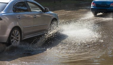 Yağmur fırtına tarafından neden olduğu sel sırasında su dolu bir yolda araba sürmek. Arabalar sokaklarda sel su üzerinde yüzer. Sıçramak üstünde belgili tanımlık makine. Büyük bir su birikintisi olan sular altında şehir yol