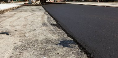 Bir otomobil şehir yol inşaatı. Yeni asfalt yolda. Yeni asfalt döşeme zaman taze sıvı, sıcak asfalt güzel akar. Soyut bitüm asfalt üzerinde graffiti tarzında akar