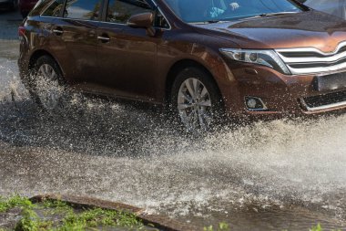 Yağmur fırtına tarafından neden olduğu sel sırasında su dolu bir yolda araba sürmek. Arabalar sokaklarda sel su üzerinde yüzer. Sıçramak üstünde belgili tanımlık makine. Büyük bir su birikintisi olan sular altında şehir yol
