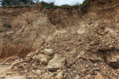 Çevreye zararlı bir bölgede dağ heyelan. Yeryüzündeki büyük çatlaklar, toprak yolu kapatan büyük katmanların inişi. Dağ yamacının yamacında baraj tehlikesi