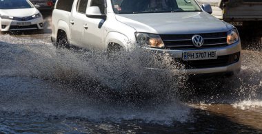 Odessa, Ukrayna -3 Temmuz 2018: yağmur fırtına tarafından neden olduğu sel sırasında su dolu bir yolda araba sürmek. Arabalar sokaklarda sel su üzerinde yüzer. Sıçramak üstünde belgili tanımlık makine. Büyük bir su birikintisi olan sular altında şehir yol
