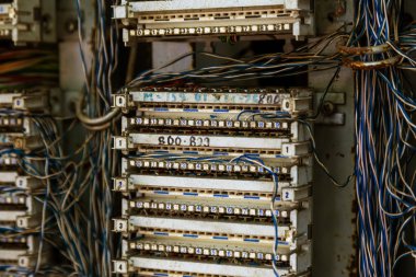Şehir sokak eski analog telefon geçiş panosunda. Kırık, yağmalanmış terk edilmiş kırık eski telefon santral sabit hat kablolu. Kablo kanalı, telefon asılı kabine teller