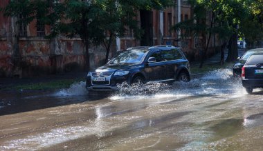 Odessa, Ukrayna -3 Temmuz 2018: yağmur fırtına tarafından neden olduğu sel sırasında su dolu bir yolda araba sürmek. Arabalar sokaklarda sel su üzerinde yüzer. Sıçramak üstünde belgili tanımlık makine. Büyük bir su birikintisi olan sular altında şehir yol