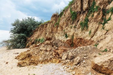 Çevreye zararlı bir bölgede dağ heyelan. Yeryüzündeki büyük çatlaklar, toprak yolu kapatan büyük katmanların inişi. Dağ yamacının yamacında baraj tehlikesi