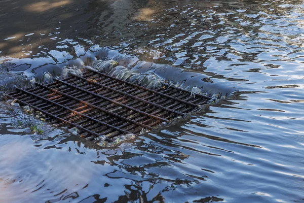 Flow of water during heavy rain and clogging of street sewage. The flow of water during a strong hurricane in storm sewers. Sewage storm system along the road to drain rain into the drainage system