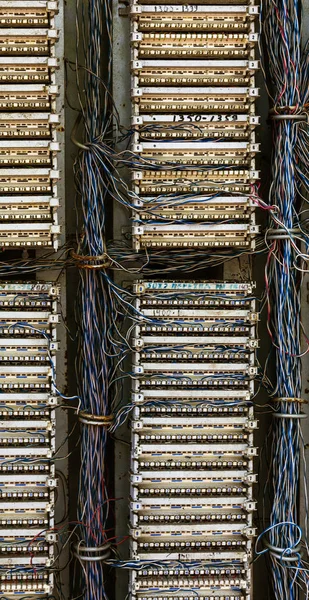 Old analog telephone switchboard in city street. Broken, looted abandoned broken old telephone switchboard wired fixed-line. Cable duct, hanging telephone wires in cabinet