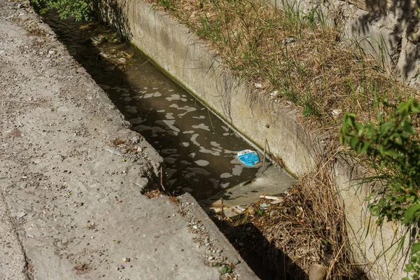 Dirty Sewage entering ground from broken pipeline to drain cement causes pollution. Cement channel for discharging dirty sewage on side of city street. ecological problem of epidemic