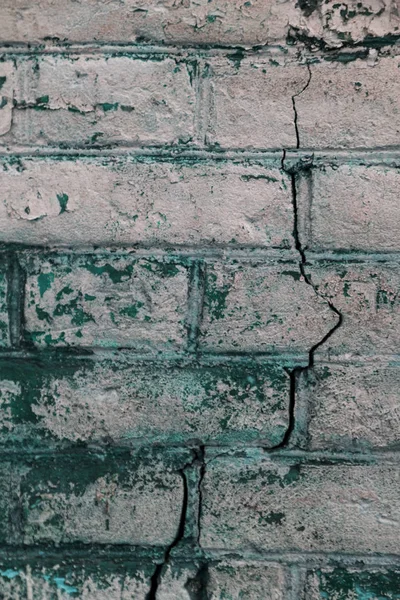 An old destroyed wall with large large cracks. Background of crack on an old wall as background for creative design. Destroyed cracked wall of building after earthquake and hurricane