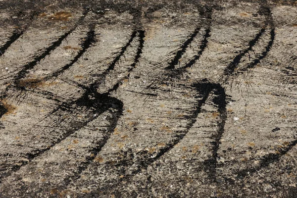 Construction of an automobile city road. New asphalt on road. Beautiful Flows of fresh liquid, hot bitumen when laying new asphalt. Abstract bitumen flows in graffiti style on asphalt