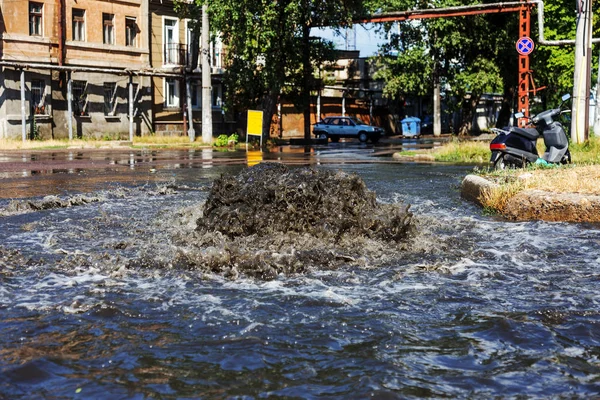 事故排污系统 水从下水道流过马路 下水道事故 突破性的排污系统 水从下水道流出 公路排水井供水系统的浇筑 — 图库照片