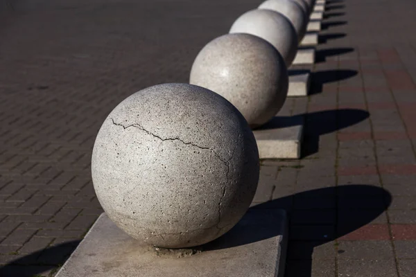 Stone balls on a city street. City design of the square. A ruler of large street decorative in large cracks of natural granite spheres. Cracks on the surface of a granite stone sphere