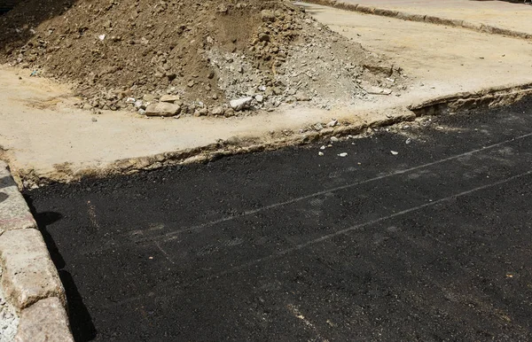Construction of an automobile city road. New asphalt on road. Beautiful Flows of fresh liquid, hot bitumen when laying new asphalt. Abstract bitumen flows in graffiti style on asphalt