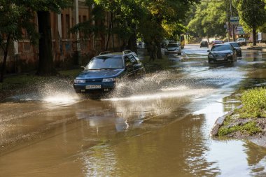 Odessa, Ukrayna -3 Temmuz 2018: yağmur fırtına tarafından neden olduğu sel sırasında su dolu bir yolda araba sürmek. Arabalar sokaklarda sel su üzerinde yüzer. Sıçramak üstünde belgili tanımlık makine. Büyük bir su birikintisi olan sular altında şehir yol