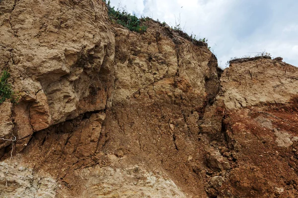 Çevreye zararlı bir bölgede dağ heyelan. Yeryüzündeki büyük çatlaklar, toprak yolu kapatan büyük katmanların inişi. Dağ yamacının yamacında baraj tehlikesi