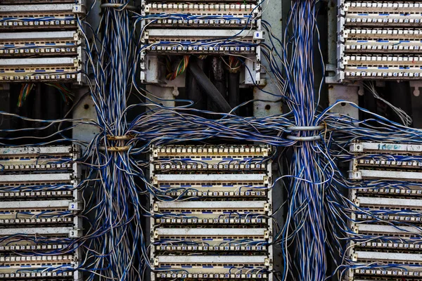 Old analog telephone switchboard in city street. Broken, looted abandoned broken old telephone switchboard wired fixed-line. Cable duct, hanging telephone wires in cabinet