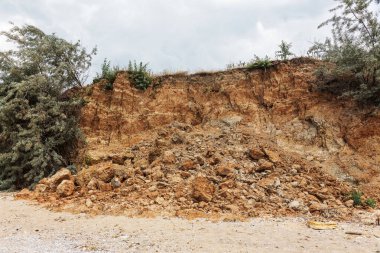 Çevreye zararlı bir bölgede dağ heyelan. Yeryüzündeki büyük çatlaklar, toprak yolu kapatan büyük katmanların inişi. Dağ yamacının yamacında baraj tehlikesi