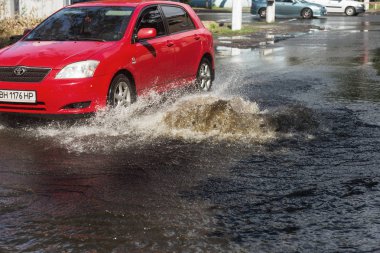 Odessa, Ukrayna -3 Temmuz 2018: yağmur fırtına tarafından neden olduğu sel sırasında su dolu bir yolda araba sürmek. Arabalar sokaklarda sel su üzerinde yüzer. Sıçramak üstünde belgili tanımlık makine. Büyük bir su birikintisi olan sular altında şehir yol