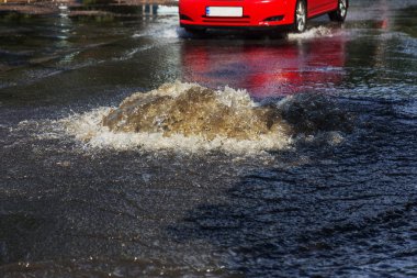 Yol kanalizasyon kapağından su akar. Lağım kanalizasyonu. Kanalizasyon sistemi kazası. Kirli lağım suyu yolda akar. Ambar çeşmesinden su akar