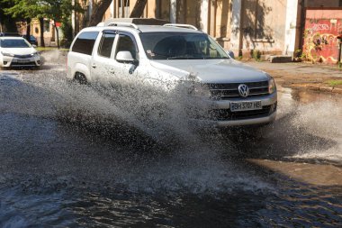 Odessa, Ukrayna -3 Temmuz 2018: yağmur fırtına tarafından neden olduğu sel sırasında su dolu bir yolda araba sürmek. Arabalar sokaklarda sel su üzerinde yüzer. Sıçramak üstünde belgili tanımlık makine. Büyük bir su birikintisi olan sular altında şehir yol