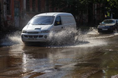 Odessa, Ukrayna -3 Temmuz 2018: yağmur fırtına tarafından neden olduğu sel sırasında su dolu bir yolda araba sürmek. Arabalar sokaklarda sel su üzerinde yüzer. Sıçramak üstünde belgili tanımlık makine. Büyük bir su birikintisi olan sular altında şehir yol