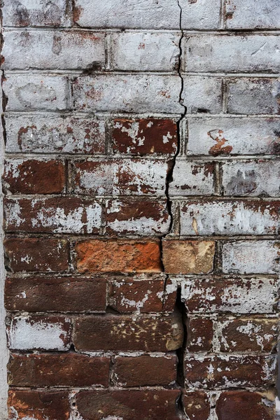 An old destroyed wall with large large cracks. Background of crack on an old wall as background for creative design. Destroyed cracked wall of building after earthquake and hurricane