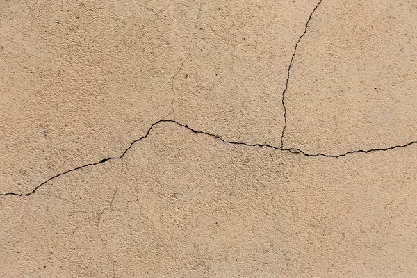 An old destroyed wall with large large cracks. Background of crack on an old wall as background for creative design. Destroyed cracked wall of building after earthquake and hurricane