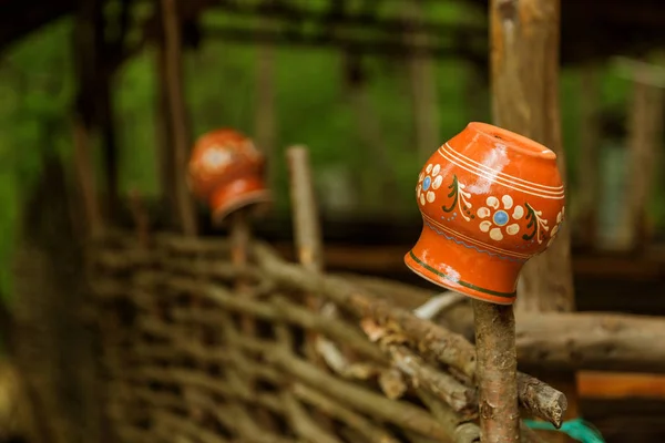 フェンスの上に粘土ヴィンテージの伝統的な鍋 農村風景 ウィッカーフェンスに伝統的な古い粘土鍋 ロシアのウクライナの村の伝統であるフェンスの上のセラミックピッチャー — ストック写真