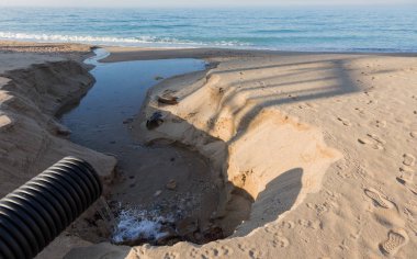 Endüstriyel Atıksu boru hattı bir şehir plajda denize sıvı endüstriyel atıkların deşarj. Bir plastik kanalizasyon borudan deniz şehir plaj kum üzerine kirli kanalizasyon akar