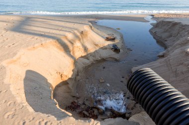 Endüstriyel Atıksu boru hattı bir şehir plajda denize sıvı endüstriyel atıkların deşarj. Bir plastik kanalizasyon borudan deniz şehir plaj kum üzerine kirli kanalizasyon akar